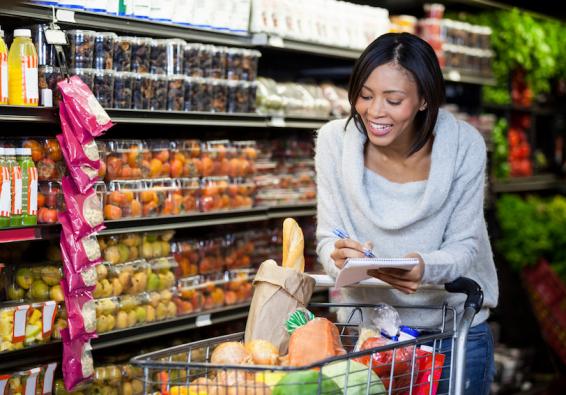 Woman reviewing grocery list in grocery store refers to HPRC for military service-specific financial resources and programs. 